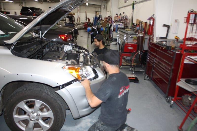  Mechanics working on vehicle repairs at Trew Auto Body Inc